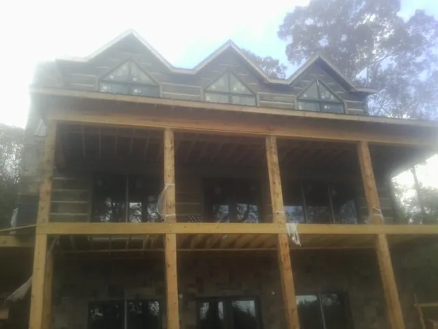 Dormers and porch framing on a large log home under construction — Roof Coating work by our crew in Fosston