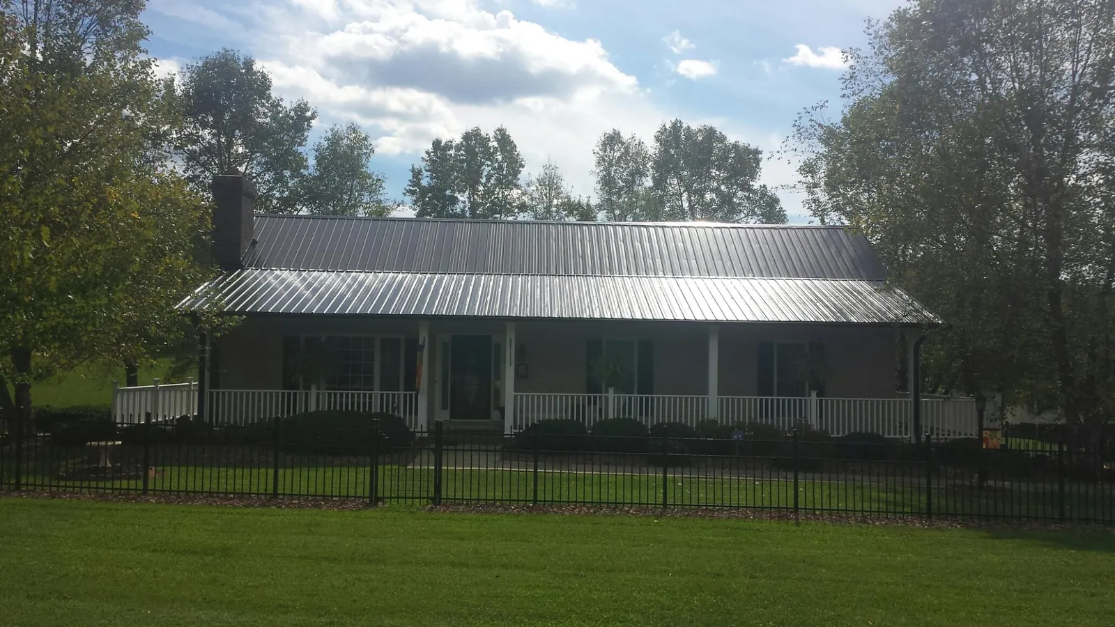 Gray metal roof on a brick ranch with a full width front porch — Gutter Guard Installation work by our crew in Fosston