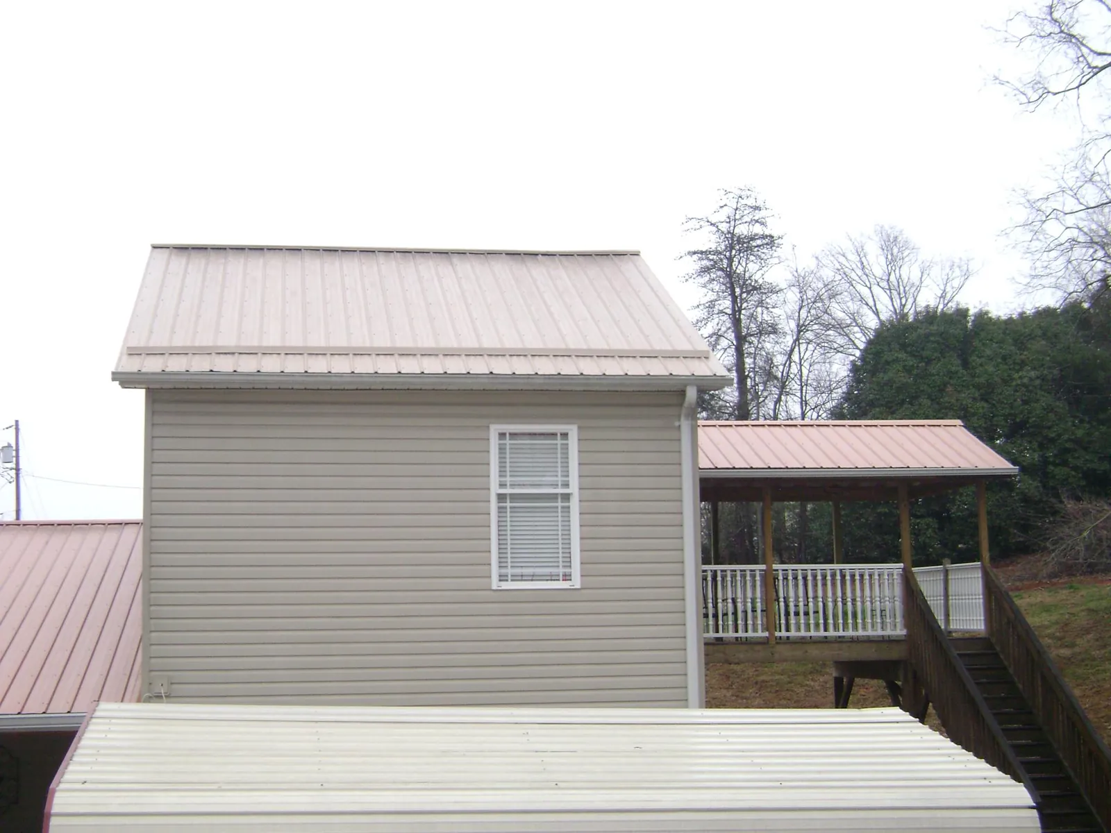 Tan metal roofs on a two story addition and attached porch, from a Roof Replacement job in Fosston