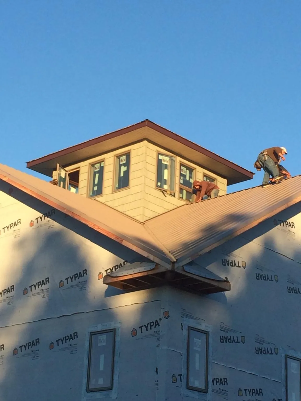 Roofers working around a rooftop cupola on a new metal roof at sunset — Roof Waterproofing in Fosston by Roofing Brothers